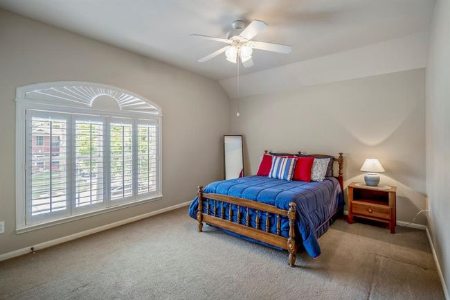 This spacious upstairs bedroom features large plantation shutters on the window overlooking the front of the home, with a vaulted ceiling adding to the room's open and airy feel. All bedrooms in the home offer the added convenience of walk-in closets. | Image 28