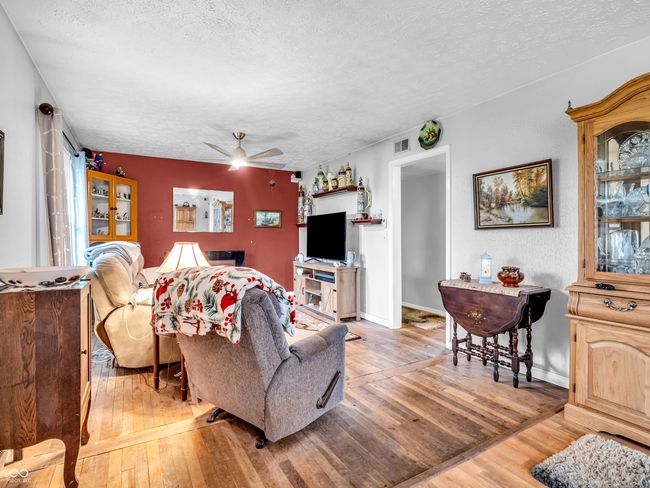 living room with a textured ceiling, visible vents, ceiling fan, and light wood-style floors | Image 10