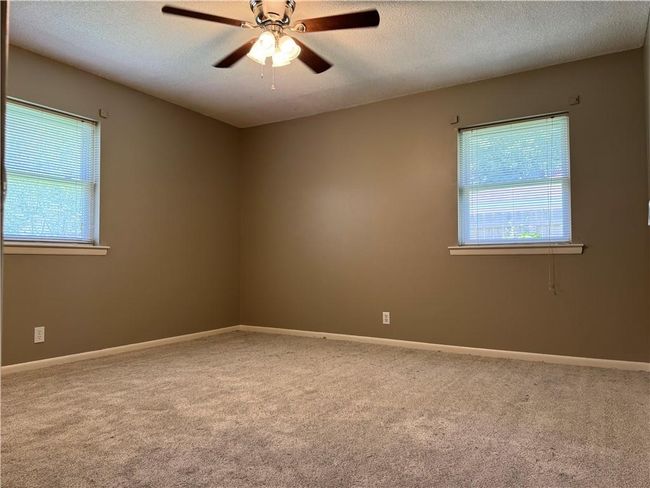 Empty room with carpet flooring, a textured ceiling, and a ceiling fan | Image 13
