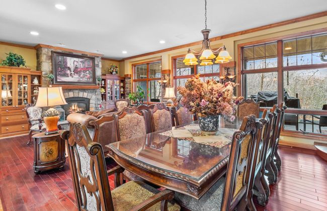 Formal Dining Room with mahogany hardwood floors, shown with connecting living room and fireplace, stone accented wall with wall sconces | Image 4