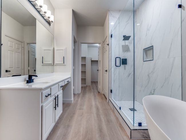 Bathroom with a marble finish shower, vanity, a freestanding bath, wood finished floors, and a walk in closet | Image 18