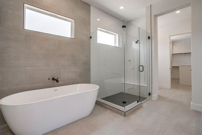 Bathroom featuring a shower stall, a freestanding bath, tile patterned floors, a walk in closet, and tile walls | Image 26