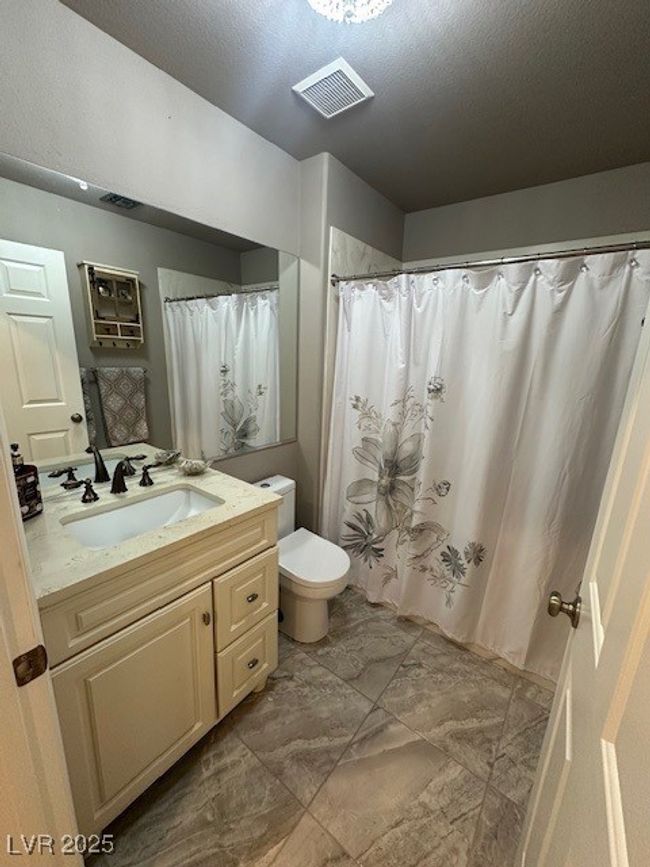Full bath featuring vanity, marble look tiles, a textured ceiling, and a shower with shower curtain | Image 11