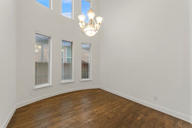 Dining room featuring baseboards, a notable chandelier, a high ceiling, and hand scraped hardwood flooring | Image 6