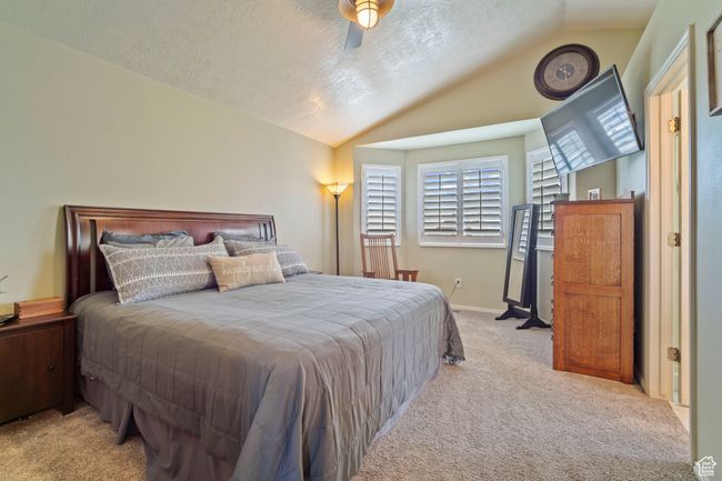 Bedroom with a textured ceiling, vaulted ceiling, carpet floors, and baseboards | Image 10