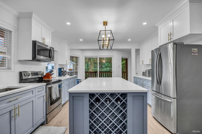 Kitchen featuring stainless steel appliances, light wood-style flooring, recessed lighting, white cabinetry, and a center island | Image 12
