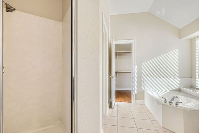 Bathroom featuring a shower stall, tile patterned flooring, a garden tub, and lofted ceiling | Image 26