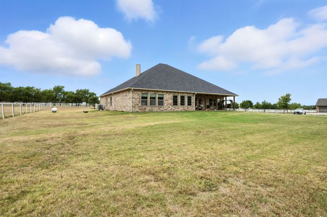 Back of property featuring a chimney, stone siding, a shingled roof, and a view of countryside | Image 39
