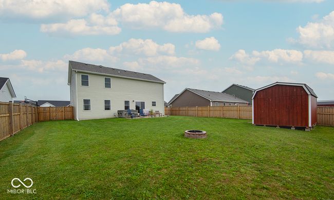 Rear view of property featuring a storage shed, a lawn, a fire pit and a fenced backyard | Image 20