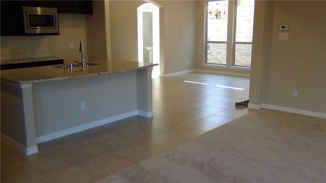 Kitchen featuring a sink, stainless steel microwave, arched walkways, light tile patterned floors, and a chandelier | Image 5