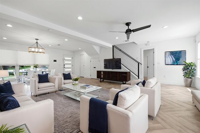 Living room with ceiling fan with notable chandelier, baseboards, recessed lighting, and stairs | Image 9
