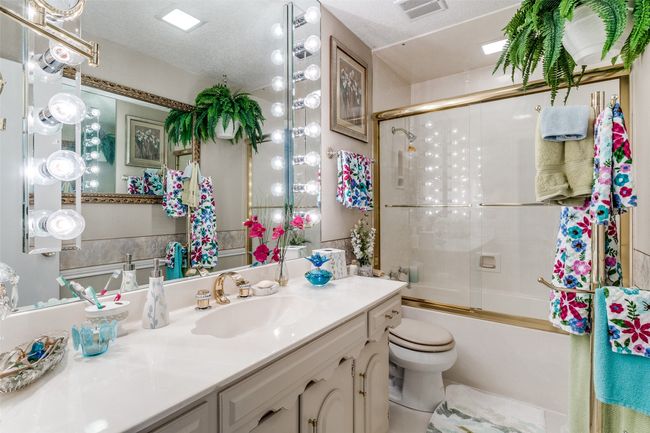 Bathroom featuring vanity and bath / shower combo with glass door | Image 18