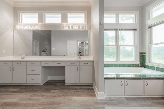 Full bath featuring double vanity, crown molding, a Jacuzzi bath, and plenty of natural light | Image 25