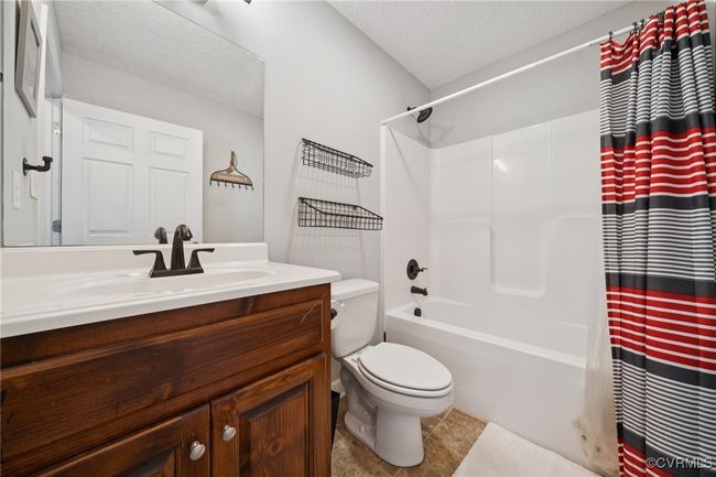 Bathroom with toilet, vanity, shower / tub combo, a textured ceiling, and tile patterned floors | Image 24