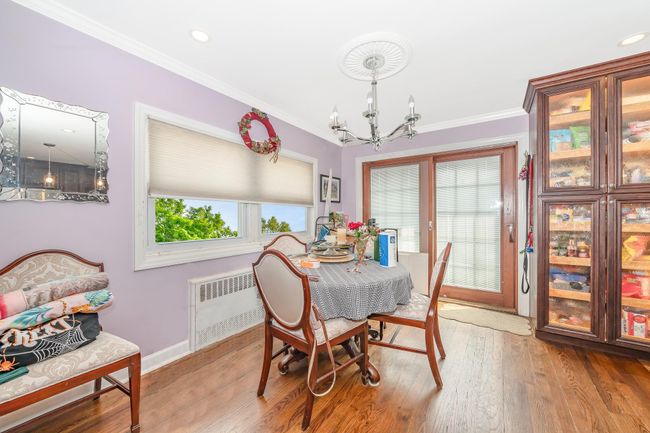 Dining area featuring radiator, a chandelier, ornamental molding, wood finished floors, and baseboards | Image 19