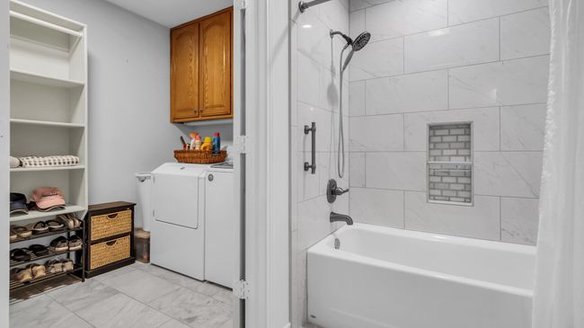 Full bathroom with marble finish floor, shower / bath combo with shower curtain, and independent washer and dryer | Image 22