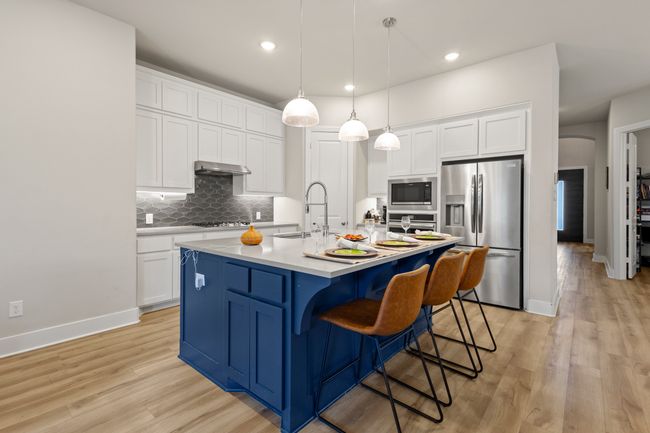 Kitchen featuring decorative backsplash, white cabinetry, and stainless steel appliances | Image 8