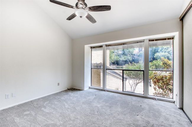 Carpeted empty room with vaulted ceiling and ceiling fan | Image 23