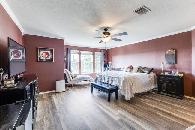 Bedroom with ornamental molding, wood finished floors, a textured ceiling, a ceiling fan, and baseboards | Image 29