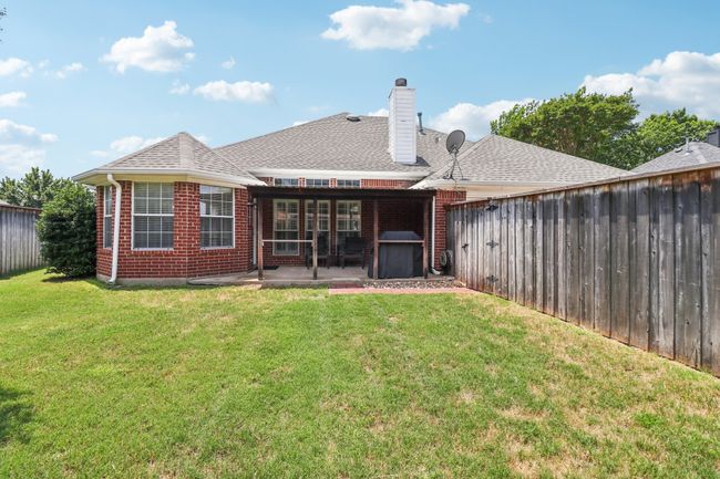 Rear view of property with a patio area, a chimney, brick siding, and a shingled roof | Image 36