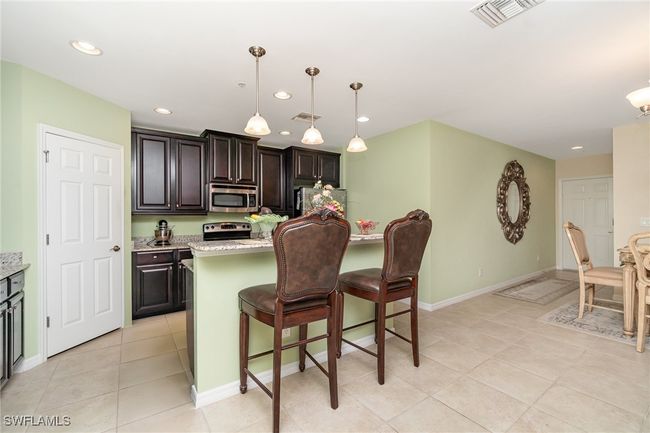 Kitchen with appliances with stainless steel finishes, light tile patterned floors, a kitchen bar, recessed lighting, and baseboards | Image 6