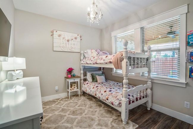 Just steps from the primary suite, this cozy bedroom features charming cased windows that overlook the back porch. With vinyl plank floors underfoot and a delicate chandelier overhead, it’s a bright and inviting space perfect for rest or creativity. | Image 25