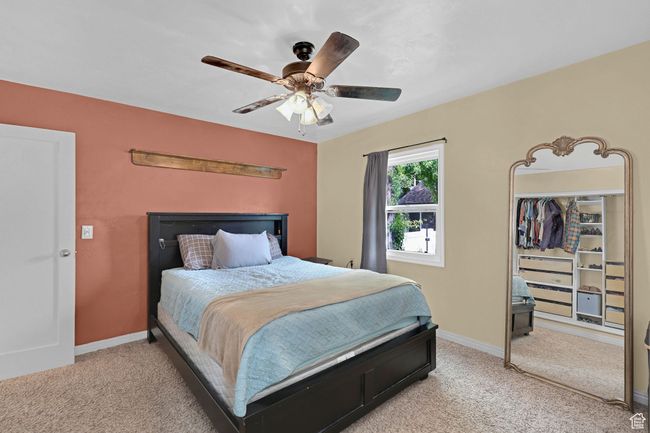 Bedroom featuring light colored carpet, a ceiling fan, and baseboards | Image 18