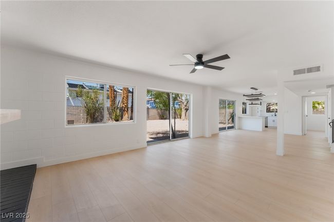Unfurnished living room with a ceiling fan and light wood-type flooring | Image 6