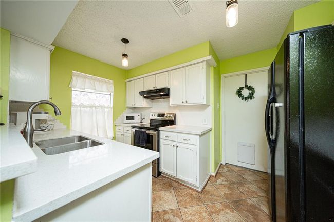 The kitchen has been updated with granite countertops, backsplash and painted cabinets. | Image 10
