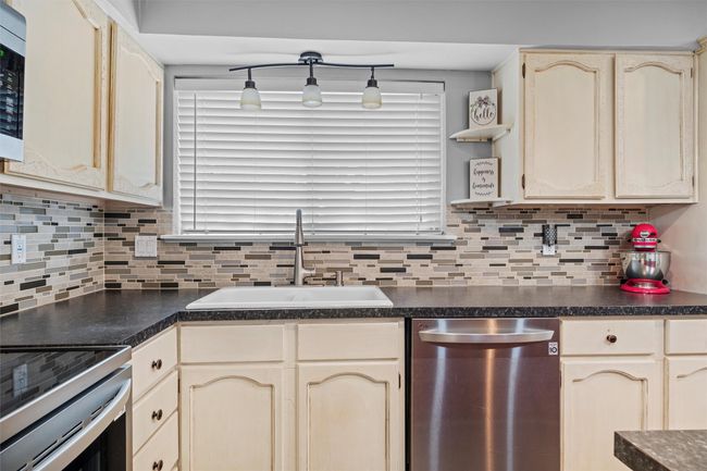 Kitchen featuring a sink, dark countertops, and appliances with stainless steel finishes | Image 8