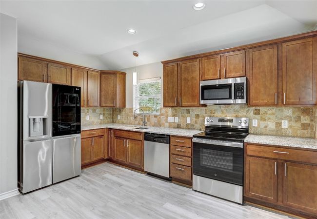 Kitchen sink with window, stainless steel appliances, recessed lighting, brown cabinets, and light stone countertops | Image 13