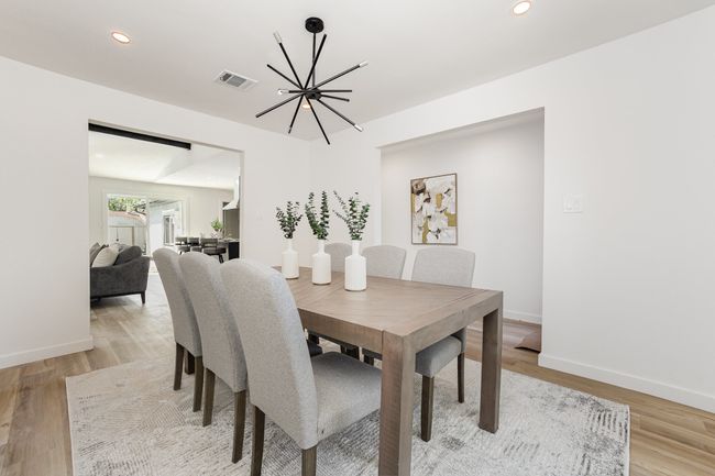 Dining area with baseboards, light wood-type flooring, a notable chandelier, and visible vents | Image 12