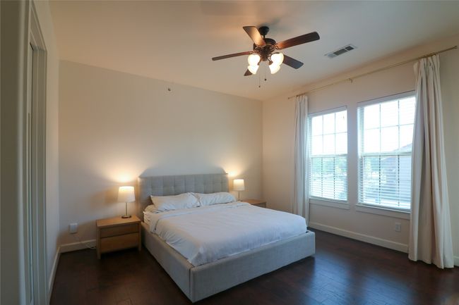 Bedroom featuring ceiling fan, baseboards, dark wood-style floors, and visible vents | Image 17