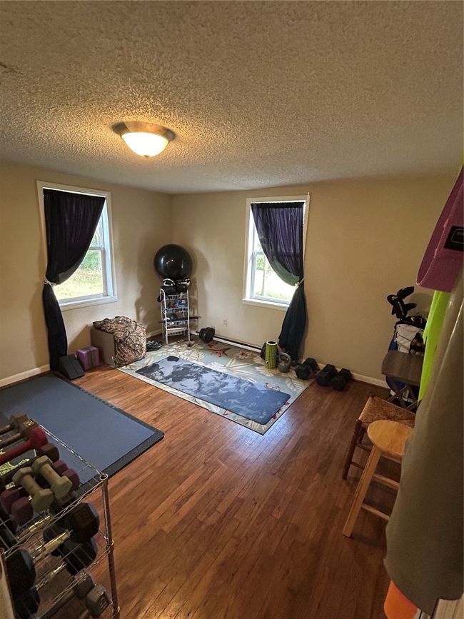 Exercise area with a textured ceiling, wood finished floors, and healthy amount of natural light | Image 13