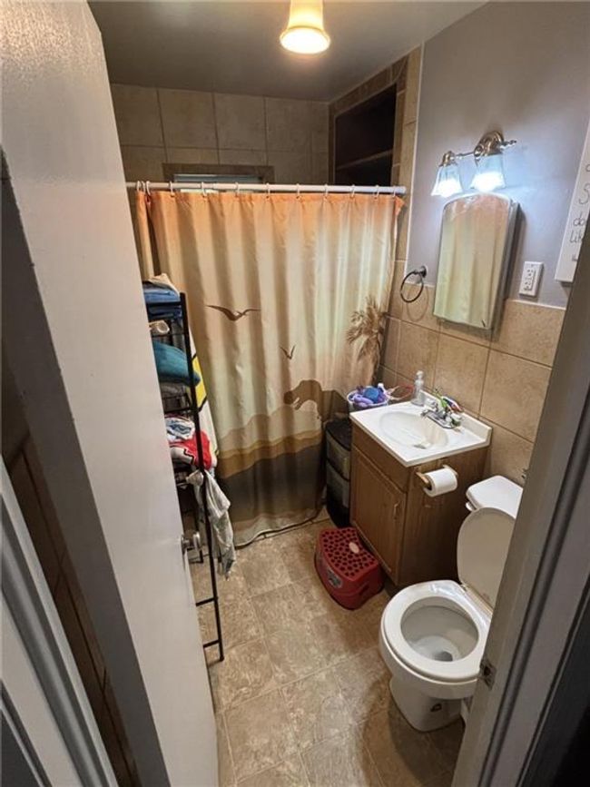 Full bathroom with tile walls, vanity, and a shower with shower curtain | Image 27