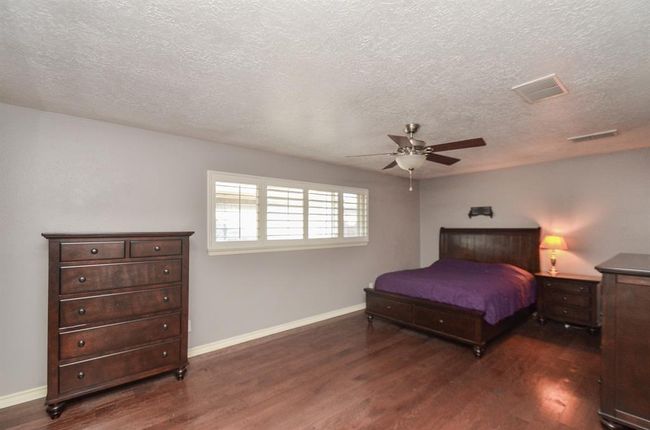 SPACIOUS primary bedroom! Beautiful flooring, plantation shutters and ceiling fan plus walk in closet | Image 14