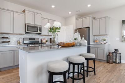 Features include stainless appliances, a spacious walk-in pantry, granite counters and a ceramic backsplash that ties the kitchen together. (Staged model in photographs, finishes may vary) | Image 1