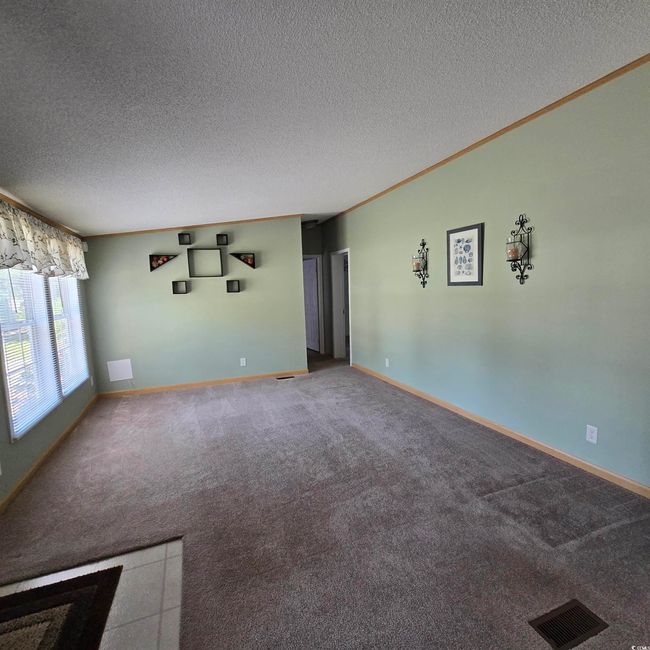 Carpeted empty room featuring a textured ceiling and ornamental molding | Image 13