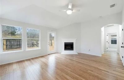 Unfurnished living room featuring light hardwood / wood-style flooring, lofted ceiling, and ceiling fan | Image 2