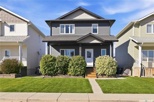 Siding exterior featuring a covered front porch, white-framed windows, and a landscaped front yard with a manicured lawn and mature shrubs | Card Image