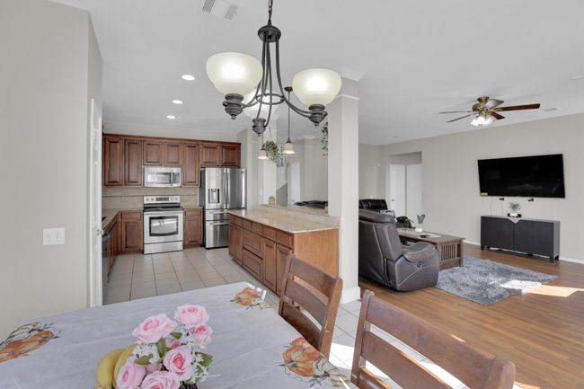 Kitchen with stainless steel appliances, visible vents, open floor plan, light countertops, and decorative backsplash | Image 12