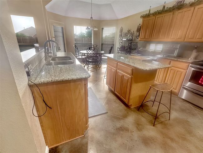 Kitchen with a sink, range, a kitchen island, light stone countertops, and vaulted ceiling | Image 24