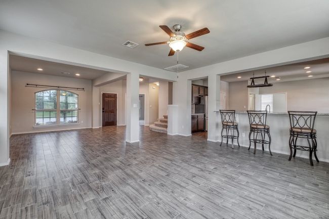 Living area with wood finished floors, a ceiling fan, stairs, and recessed lighting | Image 7