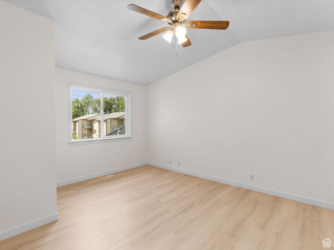 Spare room with light wood-style floors, vaulted ceiling, and ceiling fan | Image 12