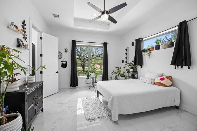 Bedroom with tile floors, multiple windows, ceiling fan, and a raised ceiling | Image 18