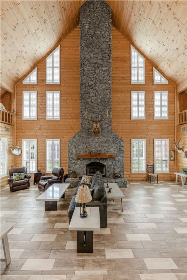 Living area with high vaulted ceiling, a stone fireplace, wood walls, healthy amount of natural light, and wood ceiling | Image 4