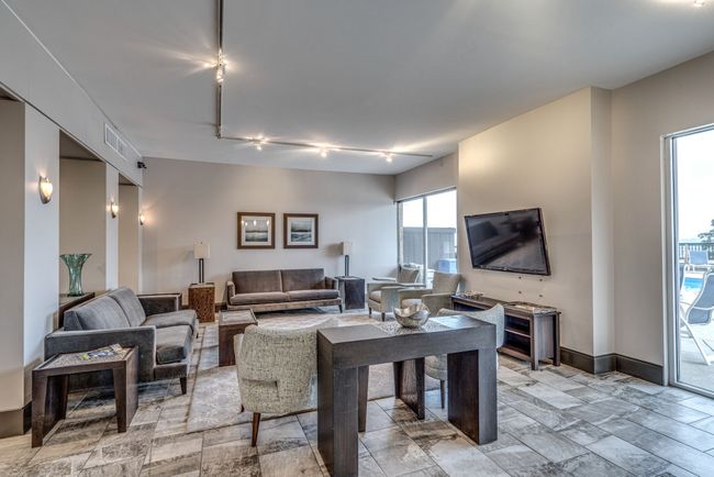 Indulge in the inviting club room living space, complete with plush sofas, entertainment options including TVs, and direct access to the pool area. | Image 36
