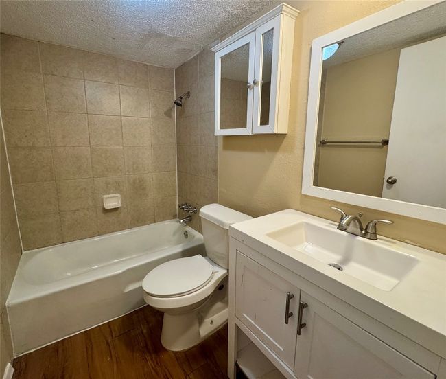 Full bath with a textured ceiling, wood finished floors, shower / washtub combination, and vanity | Image 7