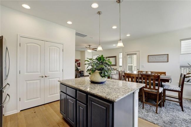 Kitchen with light wood finished floors, a kitchen island, pendant lighting, ceiling fan, and light stone countertops | Image 11