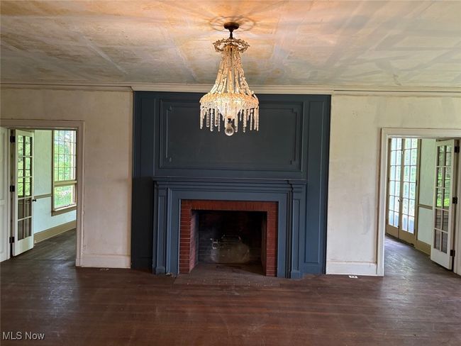 Detailed view of a chandelier, wood finished floors, and a fireplace | Image 5